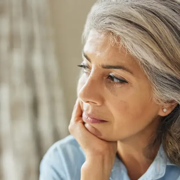 Head And Shoulders Shot Of Thoughtful Mature Woman Looking Out Of Window At Home