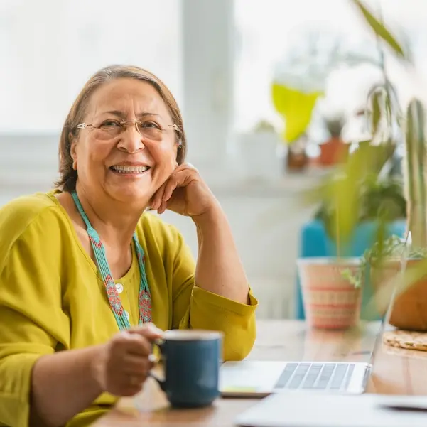 Senior woman smiling while using laptop at home